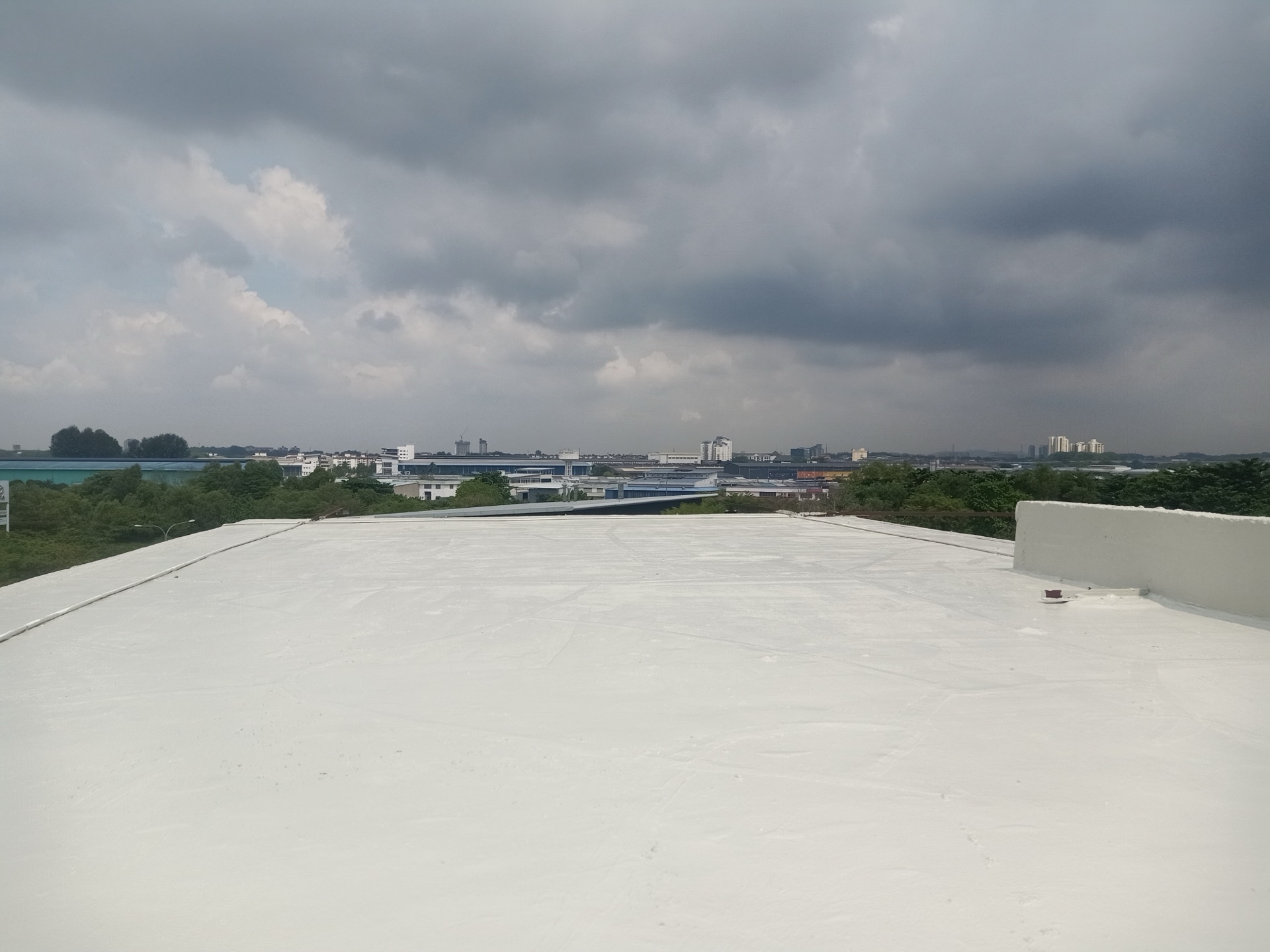 Coated industrial roof at CCN Puchong, with raised edges and the surrounding skyline.